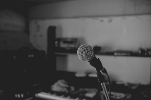 Artistic black and white shot of a music studio with a focus on a microphone. Perfect for music-themed projects.
